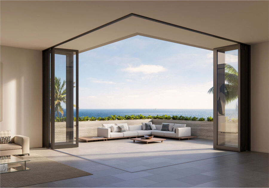 A WinDoor corner glass wall opened fully to an ocean-view terrace, showing the 90-degree corner geometry that takes the post out of the view.